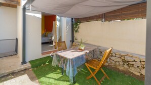 An outdoor patio with a table and chairs, a potted plant, and a covered area. - Studio Apartment 'La Dolce Vita 2' with Shared Pool, Private Terrace and Air Conditioning (Lambesc)