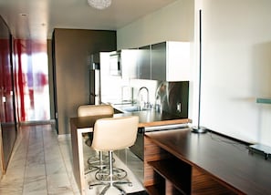 A modern kitchen with a built-in oven, stainless steel appliances, and a bar area with stools. - Palms Place Hotel Mountain View with Open Balcony (Las Vegas)