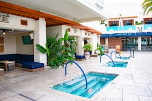 Un espace piscine comprenant plusieurs piscines, des coins salon et des plantes en pot.
