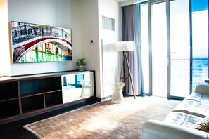 A modern living room with a large window, a sofa, a floor lamp, and a painting on the wall. - Palms Place Hotel Mountain View with Open Balcony (Las Vegas)