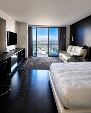 A modern hotel room with a large bed, a flat-screen TV, a sofa, and a view of the cityscape through floor-to-ceiling windows. - Palms Place Hotel Mountain View with Open Balcony (Las Vegas)