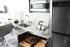 Une cuisine moderne équipée d’appareils électroménagers en acier inoxydable, d’une bouilloire et d’un meuble à tiroirs.
