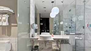 A modern bathroom with a marble sink, glass shower enclosure, and a visible toilet.