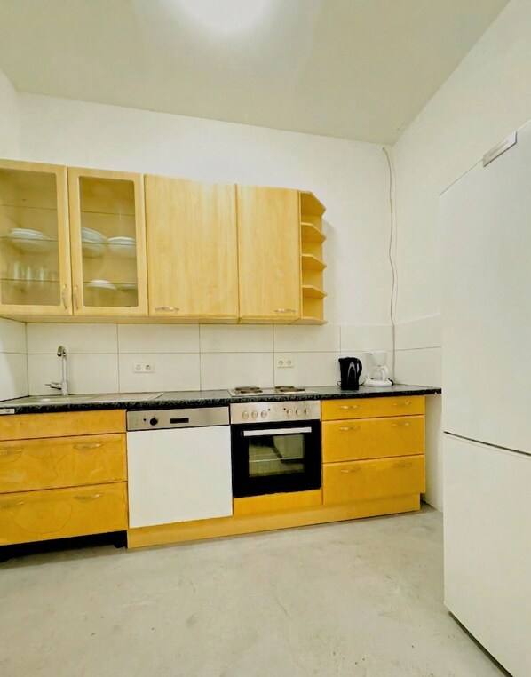 A kitchen with wooden cabinets, a dishwasher, an oven, and a coffee maker.