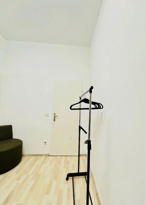 A room with a wooden floor, a black coat rack, and a closed door.