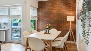 Un coin repas avec un mur en briques, une table blanche et des chaises.
