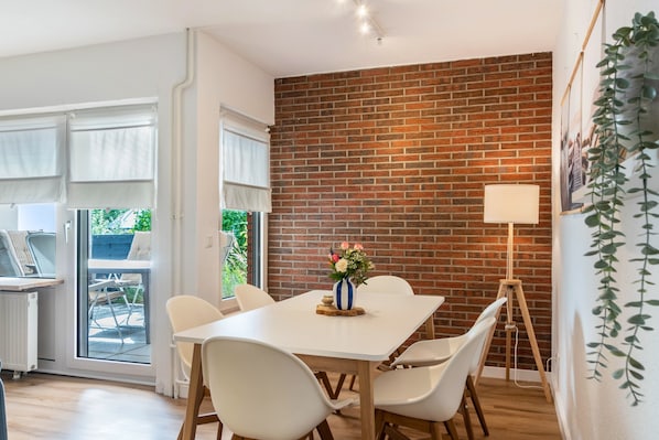 A dining area with a brick wall, white table, and chairs.