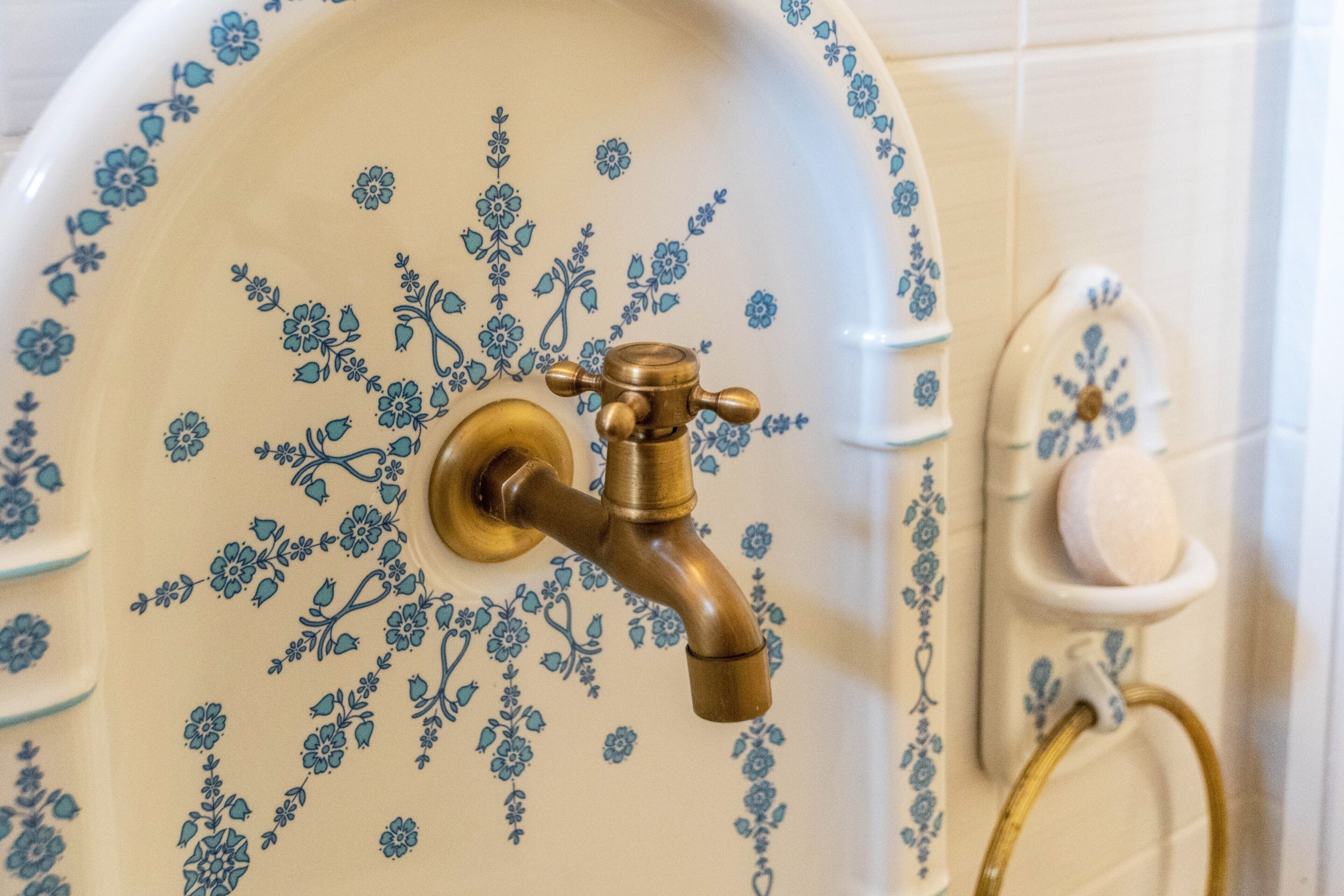 Een badkamer met een decoratieve wasbak, een messing kraan en een zeepbakje.
