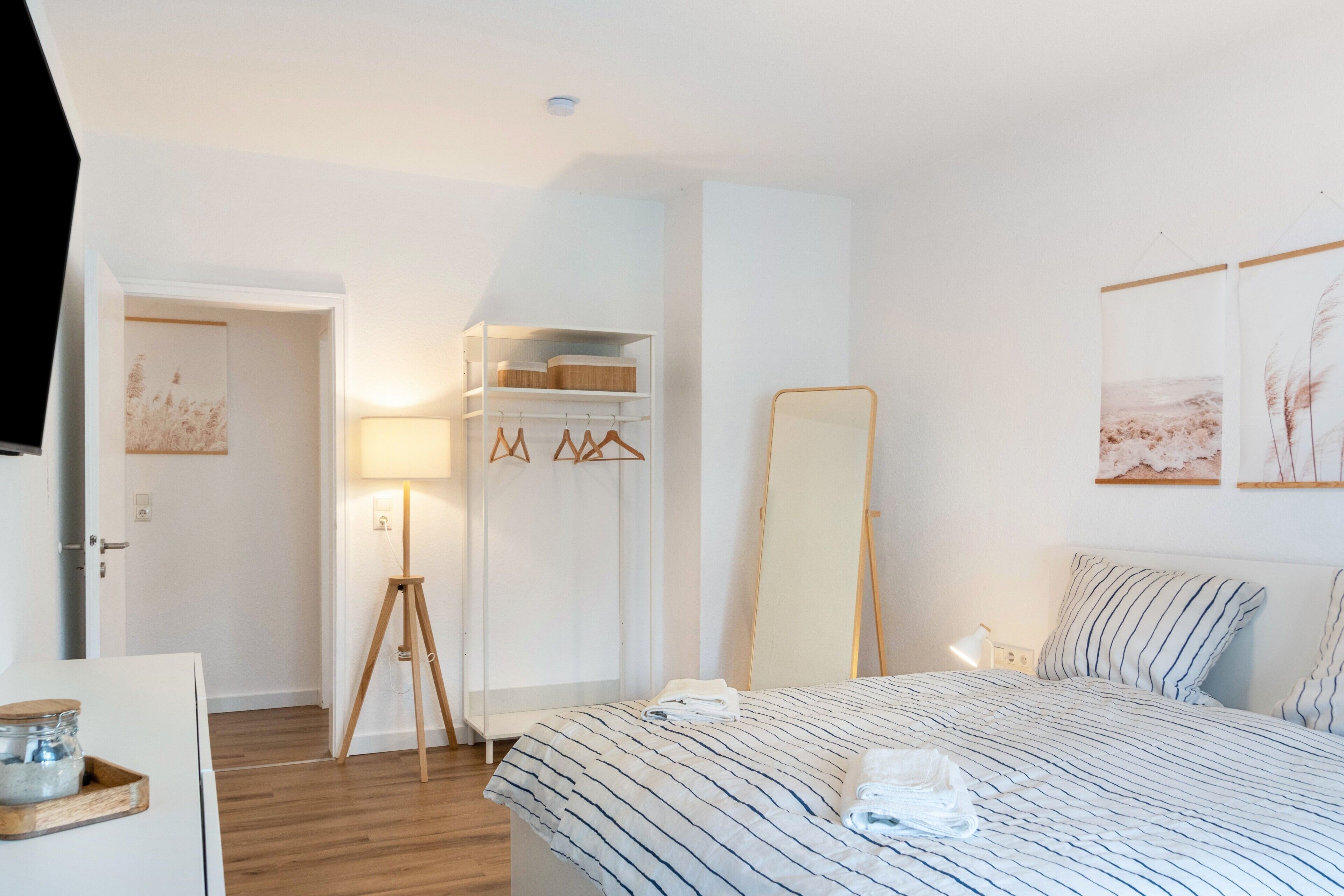 Une chambre à coucher avec un lit, une table de chevet, une lampe, une armoire et un miroir.