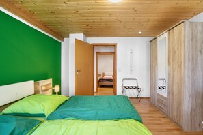 Een kamer met een bed, een kledingkast, een deur naar een andere kamer en een hangstoel.