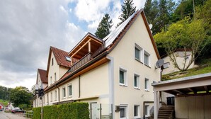 A residential building with a sloped roof, satellite dish, and a gated entrance. - Apartment 'Ferienwohnung Annette' with Shared Terrace and Wi-Fi (Gomadingen)