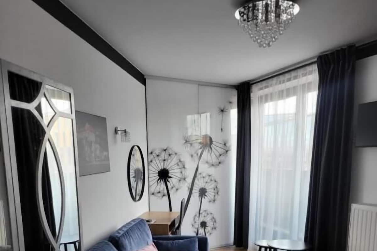 Uma sala de estar moderna com um sofá azul, uma mesa de jantar e um candelabro.