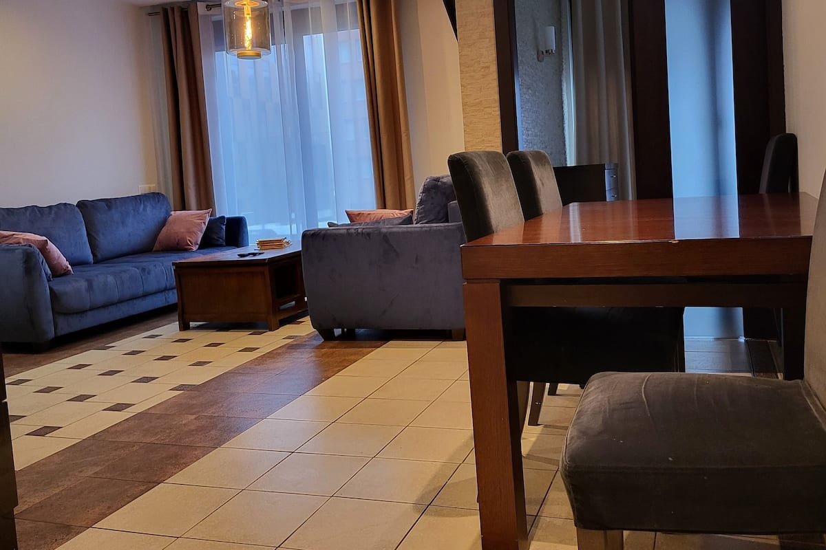 Uma sala de estar moderna com um sofá, uma mesa de jantar e uma mesa de centro.