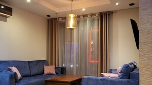 Un salon moderne avec deux canapés bleus, une table basse en bois et un luminaire suspendu.