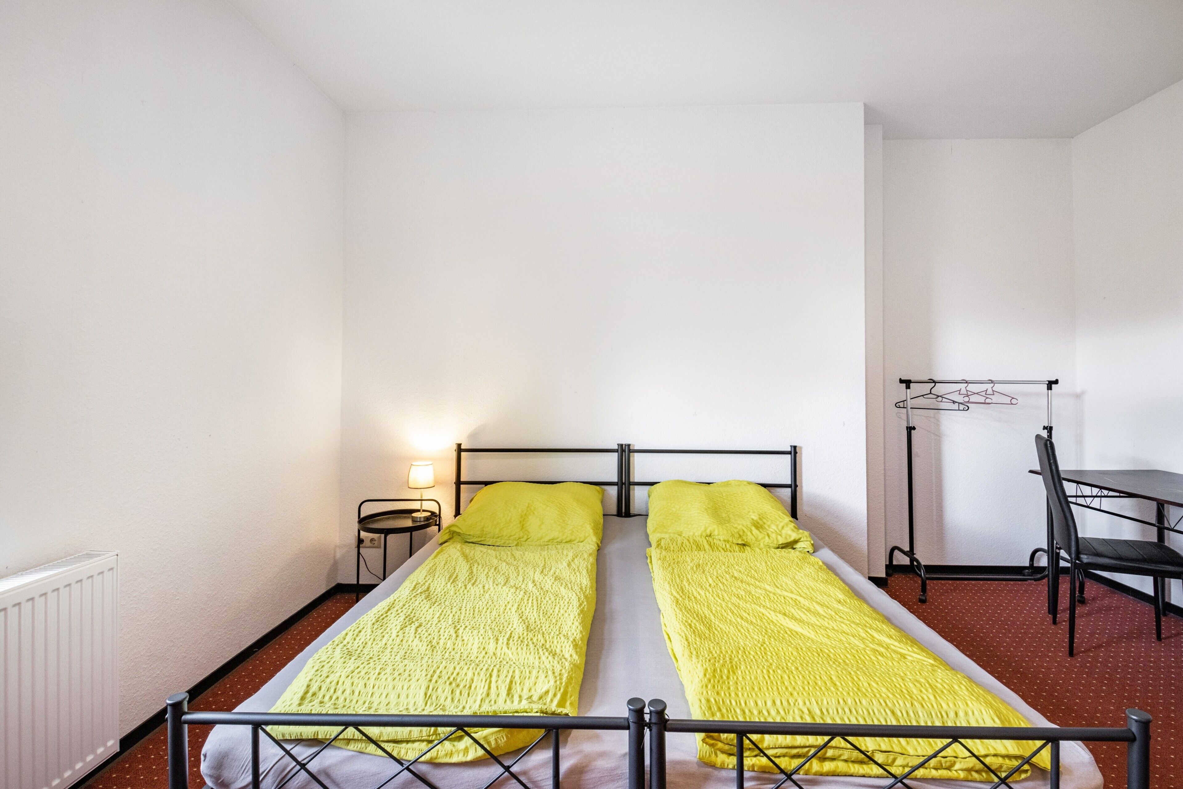 A single room with a bed, a desk, and a chair.