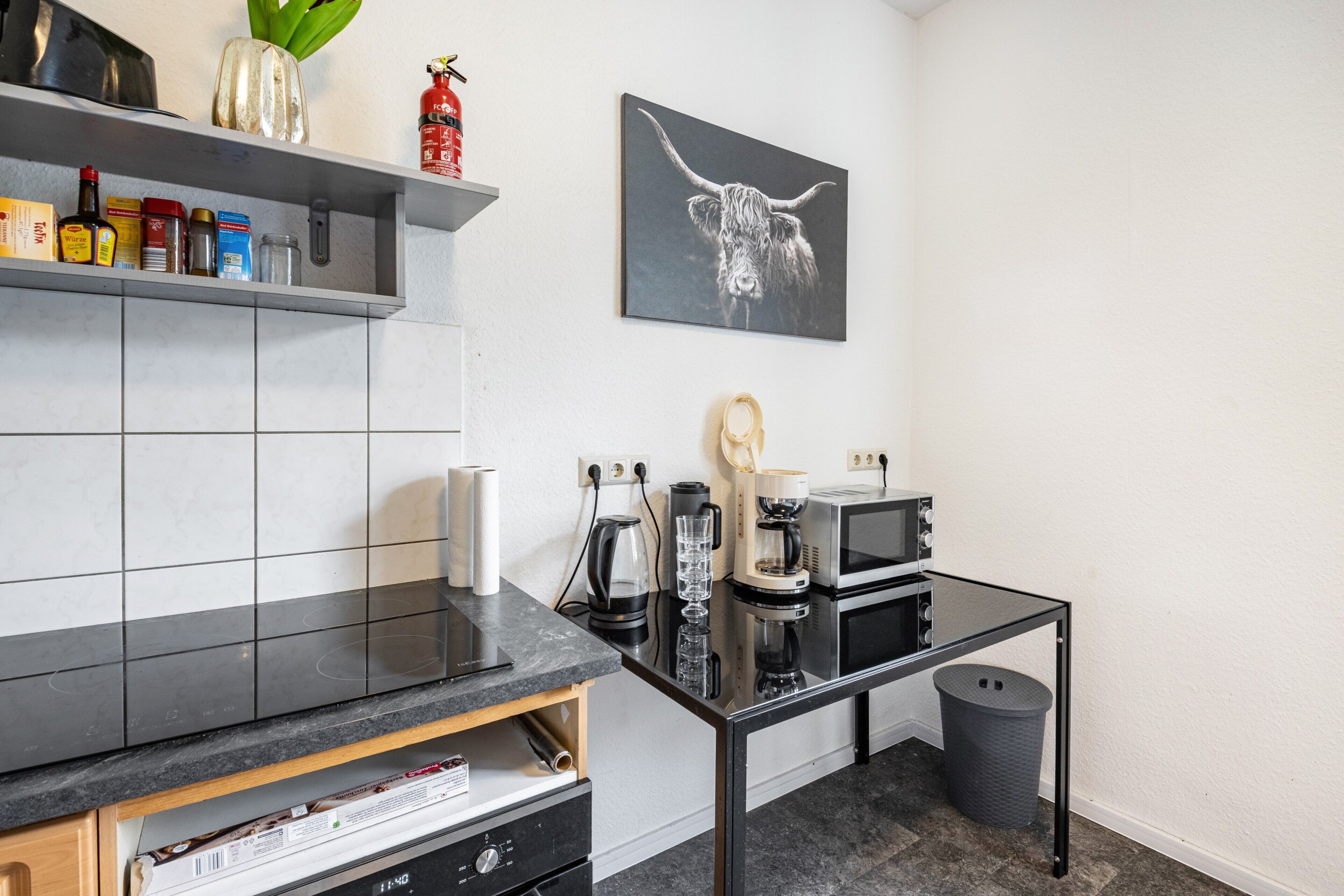 Une cuisine moderne dotée d’un plan de travail noir, d’une machine à café, d’un grille-pain et d’un four à micro-ondes.