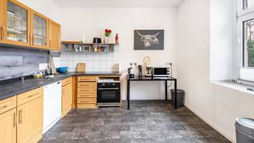 A kitchen with wooden cabinets, a dishwasher, a stove, a black countertop, a sink, a window, and a wall-mounted picture of a bull.