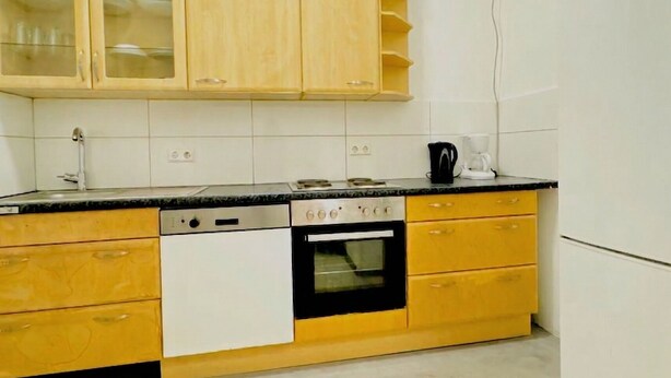 A kitchen with wooden cabinets, a dishwasher, an oven, and a coffee maker. - Cozy Room Near FAC Platz | Shared Flat (Vienna)