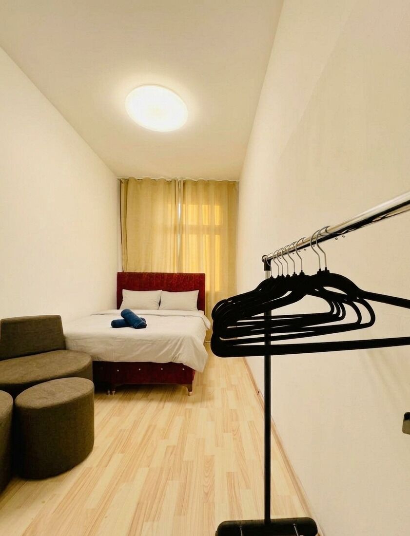 Ein Hotelzimmer mit Bett, Stuhl, Kleiderstange und Deckenleuchte.
