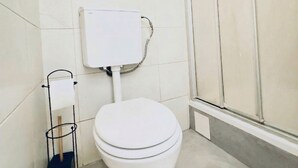 A bathroom with a toilet, a toilet paper holder, and a shower area. - Cozy Room Near FAC Platz | Shared Flat (Vienna)