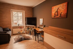 Un salon moderne avec un canapé, une table à manger, un téléviseur et un tableau accroché au mur.