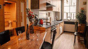 Una cocina moderna con armarios de madera, horno integrado, lavaplatos y un comedor con mesa y sillas.