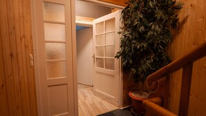 Een houten interieur met een deur, een deurmat en een plant in pot.
