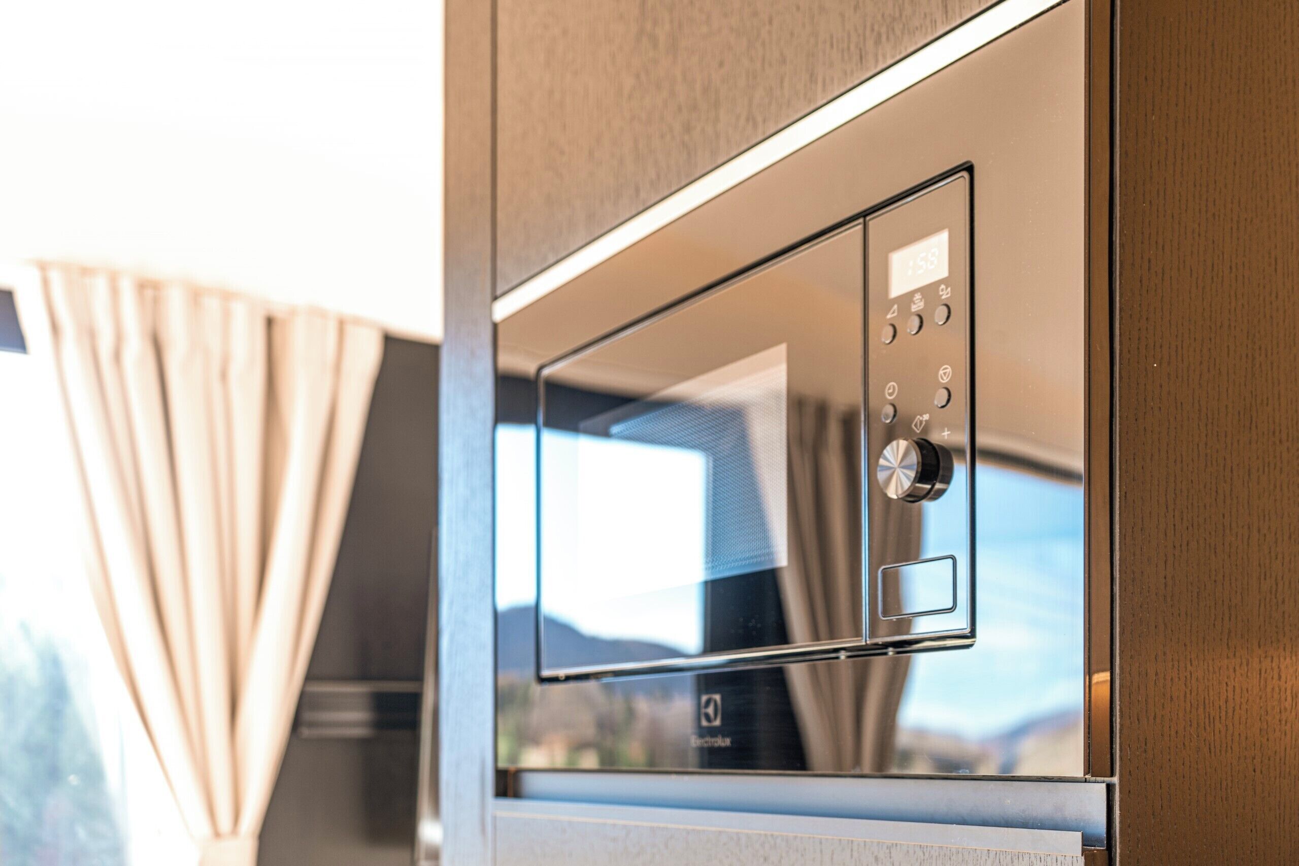 A modern kitchen with a built-in microwave and a digital display.