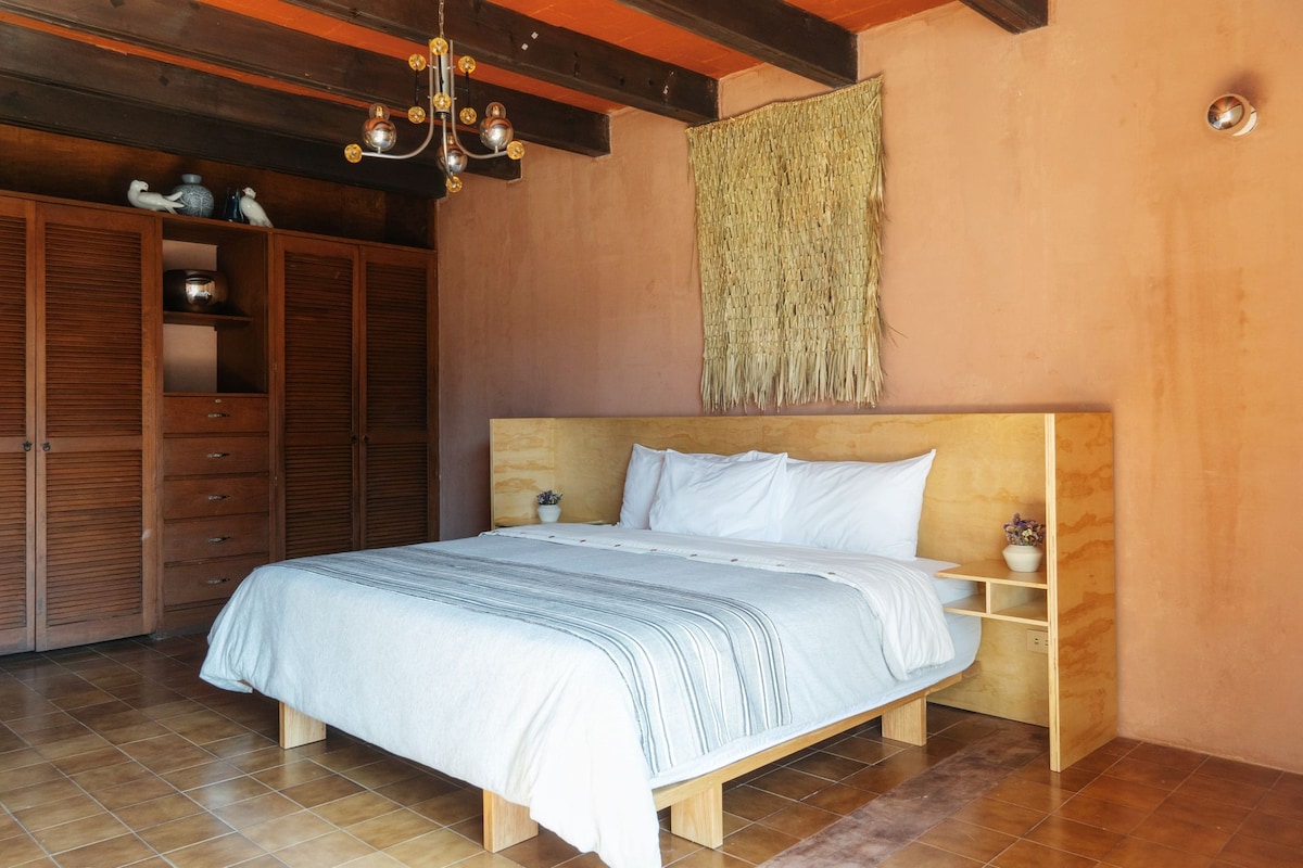 A bedroom with a wooden bed, a nightstand, a wardrobe, and a hanging tapestry.