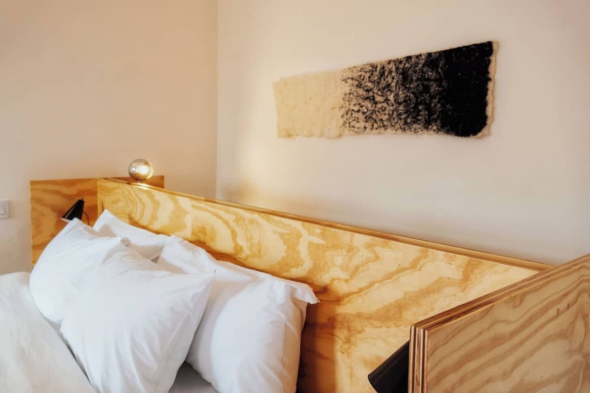 Uma cama com roupa de cama branca e cabeceira de madeira.
