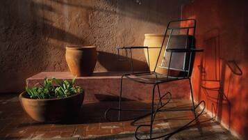 Un espacio de estar al aire libre de estilo rústico con una silla de metal, macetas de terracota y una planta en maceta.