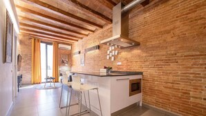 A kitchen with exposed brick walls, a central island with bar stools, and a modern stove.
