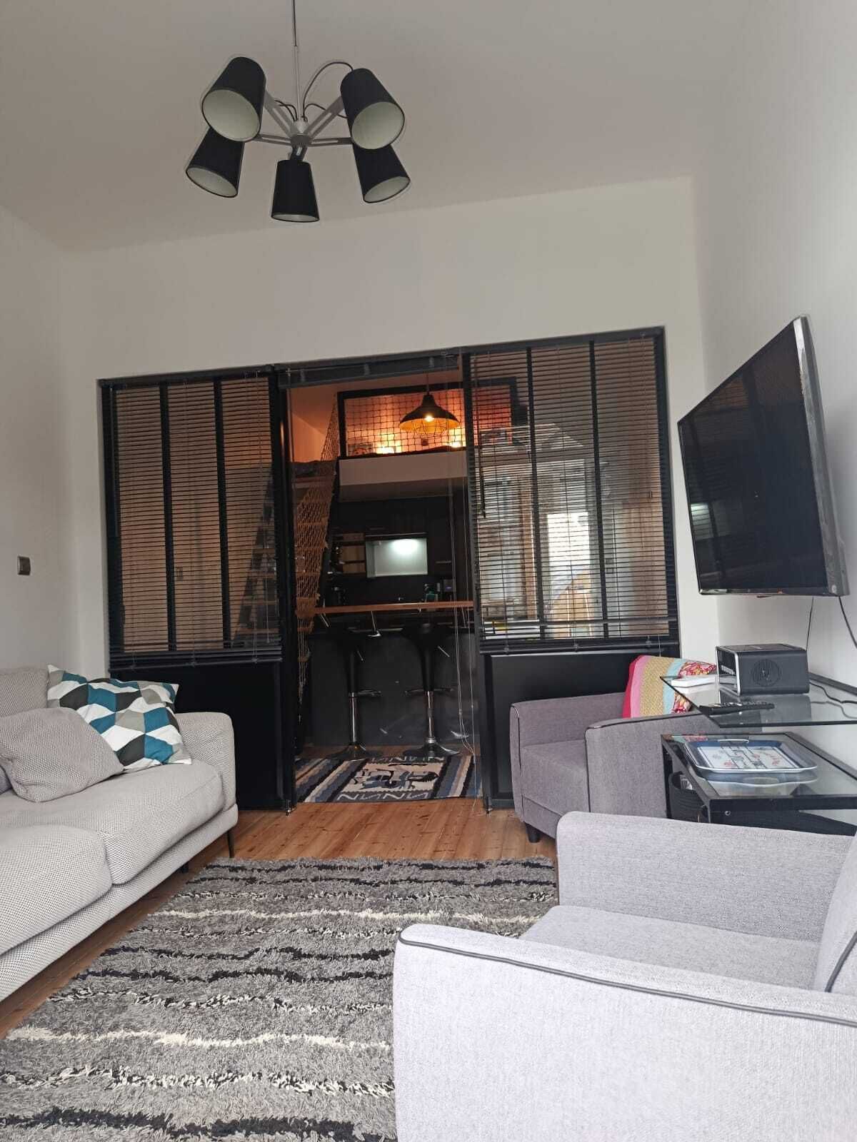 A living room with a sofa, a coffee table, a TV, and a ceiling light fixture.