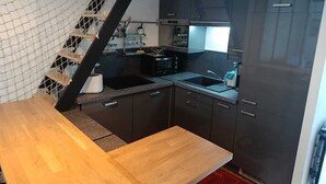 A compact kitchen with dark cabinets, a microwave, and a sink. - FI Bis Saint Malo (Saint-Malo)