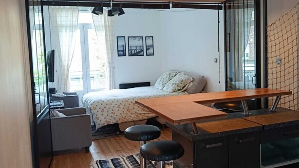 A compact, modern kitchen with a wooden countertop, bar stools, and a hanging light fixture. - FI Bis Saint Malo (Saint-Malo)