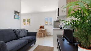 A modern living room with a dark sofa, a small desk, a television, and a potted plant. - Holidays 'La Lajita Beach Studio' with Sea View, Wi-Fi and Air Conditioning (La Lajita)