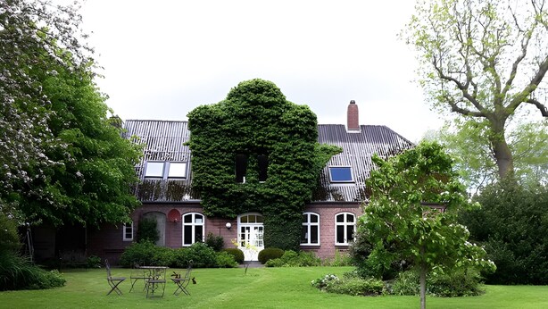 A large, traditional brick house with a symmetrical facade, a central entrance, and a well-maintained lawn.