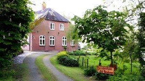 A red brick building with multiple windows and a gravel path leading to it.