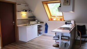 Een compacte keuken met een raam, een ingebouwde oven en een klein eethoekje.