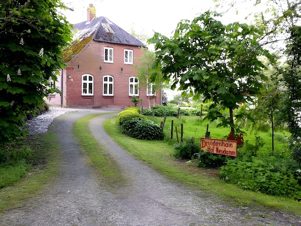 A red brick building with multiple windows and a gravel path leading to it.