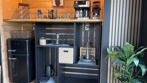 A compact kitchenette with a coffee maker, kettle, and storage containers.