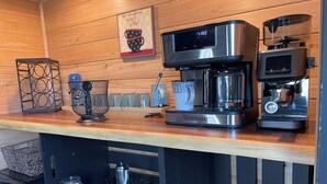 A kitchen counter with a coffee maker, a kettle, and a coffee grinder.
