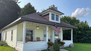 A two-story house with a porch, a small garden, and an American flag.