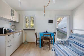 A compact kitchen with a dining table and chairs, a sofa, and a view of the outdoors.