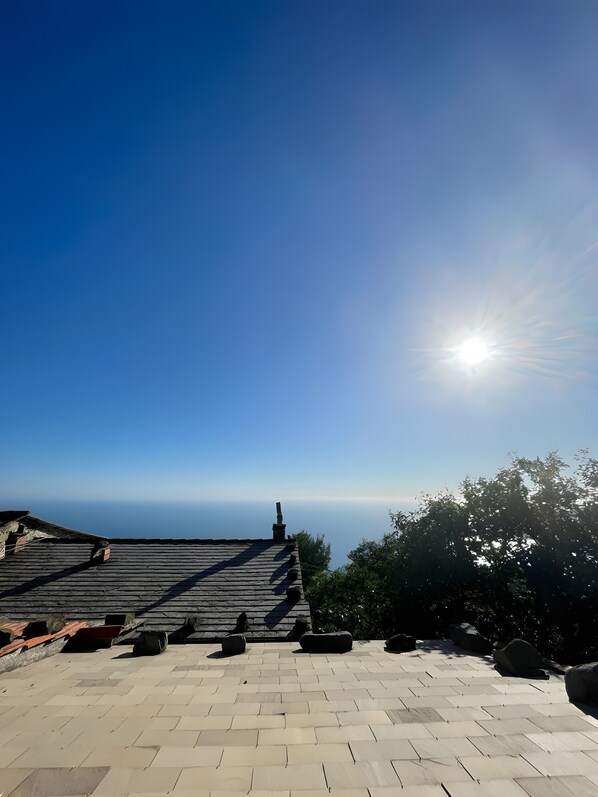 Una terraza en la azotea con vistas despejadas al horizonte, baldosas de piedra y una chimenea.