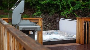 Un bain à remous sur une terrasse en bois, avec une balustrade en bois.