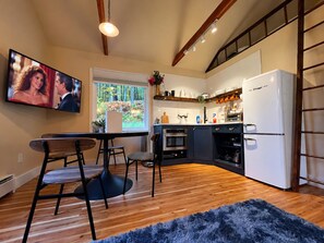 Eine moderne Küche mit Einbauofen, einem weißen Kühlschrank und einem Essbereich mit Tisch und Stühlen.