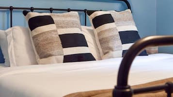 A bed with a metal frame, white bedding, and two checkered pillows.