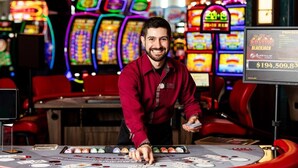 Une salle de casino avec une table de blackjack, plusieurs machines à sous et une personne debout derrière la table.