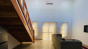 A modern interior with a staircase, a sofa, and a TV mounted on the wall. - Amaryllis Residences Mount Pleasant (Blantyre)